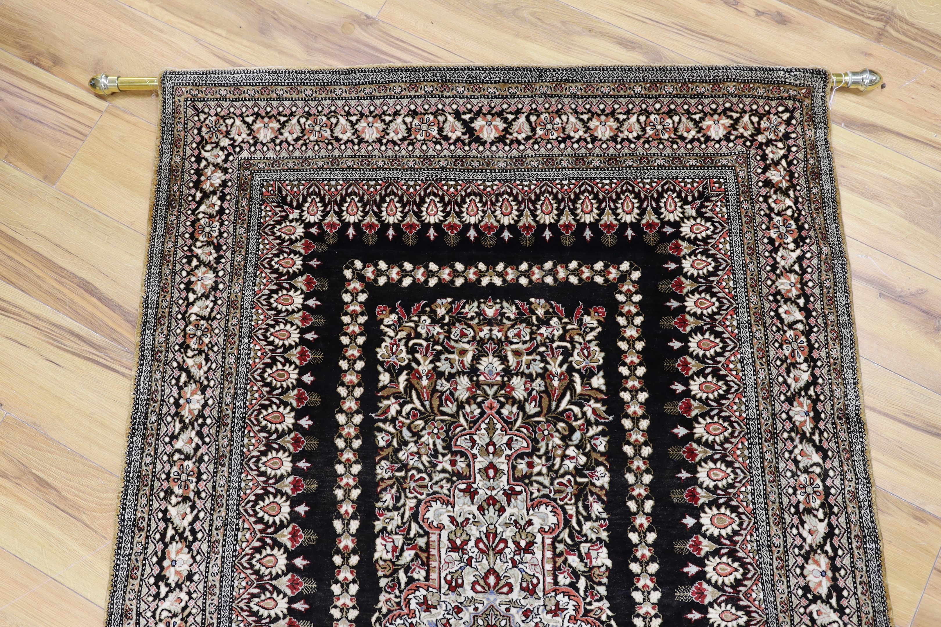 A Persian Qum silk rug, mounted as a wall hanging on a brass rod, 168 x 105cm